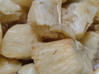 Fried cassava, golden yellow in color and crispy texture can be seen filling the entire frame,...