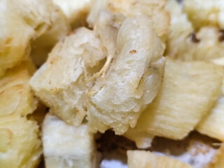 Fried cassava, golden yellow in color and crispy texture can be seen filling the entire frame,...