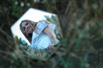 girl looking at reflection in mirror in park. High quality photo