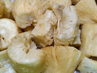 Fried cassava, golden yellow in color and crispy texture can be seen filling the entire frame, showing details of the fibers and soft inside