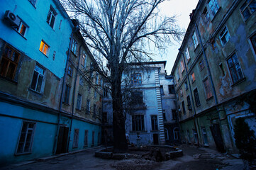 An aged urban Odessa courtyard showcases decaying buildings under the dim twilight. Emphasizing...