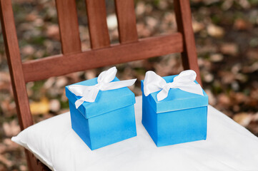 Two Blue Gift Boxes with White Ribbons on a Rustic Chair