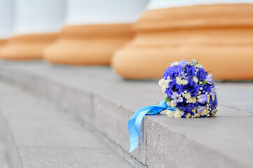 A delightful bouquet of blue and white flowers lies upon stone stairs, adorned with a soft ribbon....
