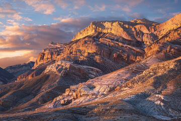 Early morning light illuminating a rugged mountain range, the warm colors of the sunrise casting long shadows and creating a breathtaking scene