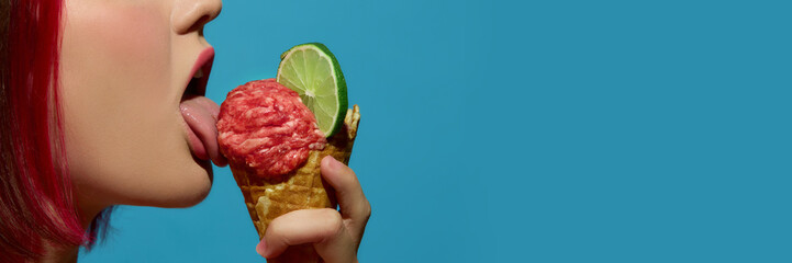 Woman licking meatball ice cream in cone with lime slice on turquoise background. Concept of...