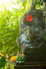Elephant sculpture covered with green moss with ritual incense stick in Bali, Indonesia.