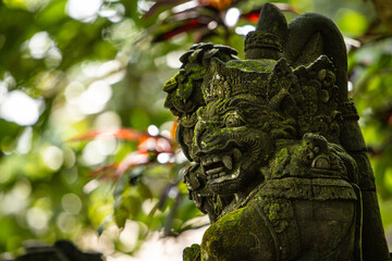 Monkey sculpture fully covered with green moss in Ubud's Monkey Forest. Bali, Indonesia.