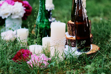 Rustic Outdoor Decor with Candles, Bottles, Flowers on Green Grass