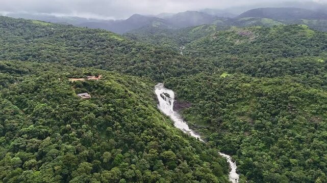 An epic aerial view of Mallalli Waterfalls overflowing amidst lush mountains and forests in spring