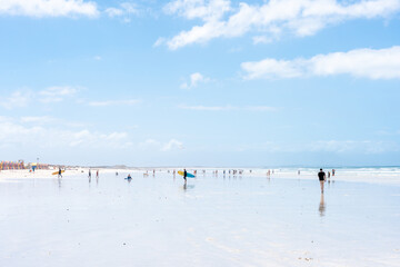 Weitläufiger Muizenberg Strand in Kapstadt mit vielen Menschen, die schwimmen, surfen und am...