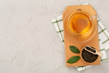 Cup of tea with dry and fresh leaves on concrete background, top view