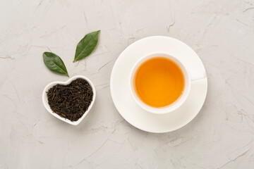 Cup of tea with dry and fresh leaves on concrete background, top view