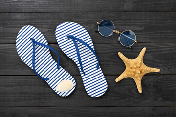 Striped blue flip flops with accessories on wooden background, top view