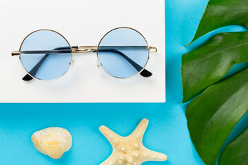 Blue sunglasses on color background, top view