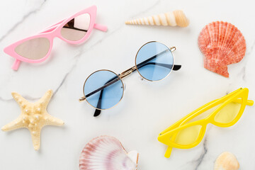 Blue sunglasses on marble background, top view