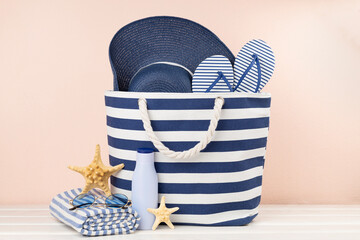 Blue beach bag with summer accessories on wooden table