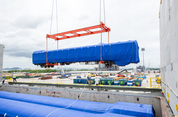 Unloading operation of project  cargo with port heavy lift cranes A crane on a large cargo ship docks loading a new passenger train at Laem Chabang Port