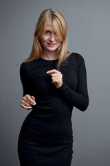 Stylish Young Woman Posing in Black Outfit Against Gray Background