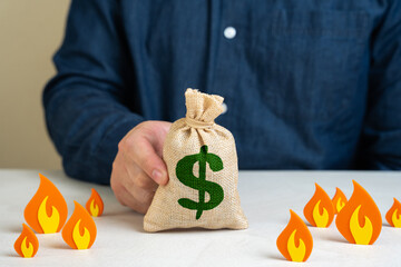 Dollar money bag surrounded by fire, concept. Save savings from depreciation, inflation and losses....