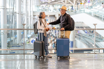 Senior asian traveler couple smiling at airport with suitcases show excitement before travel,...