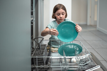 Child loads dishwasher. Everyday life concept.