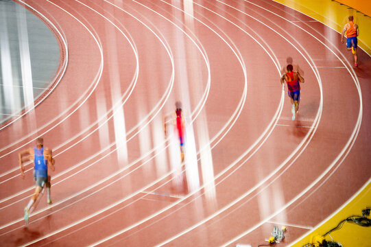 Abstract track and field photo capturing sprinters on an athletics track. Shot through glass, the image creates a double exposure effect. A creative photo file for athletics projects.