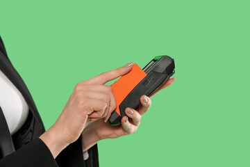 Woman using handheld device for contactless payment in a bright green environment during a busy...