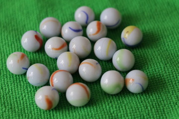 Una toma de cerca  de varias canicas o metras de diferentes tamaños sobre una tela de color verde