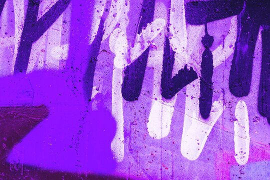 Vibrant graffiti featuring neon purple and white on textured surface. 80s retro style, bold contrasts. Urban, street art, digital backgrounds, flyers.