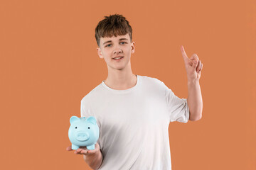 Young boy holds a blue piggy bank and points upwards, symbolizing financial savings and financial...