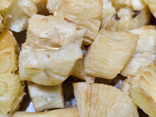 Fried cassava, golden yellow in color and crispy texture can be seen filling the entire frame, showing details of the fibers and soft inside