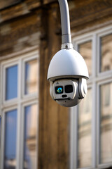 Modern street surveillance camera mounted on a curved pole against an urban backdrop. The camera's...