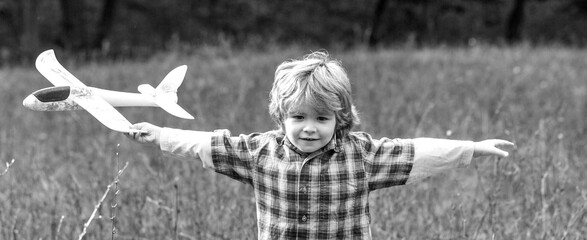 Little kid dreams of being a pilot. Child playing with toy airplane. Happy child playing outdoors. Happy boy play airplane. Black and white © Yevhen