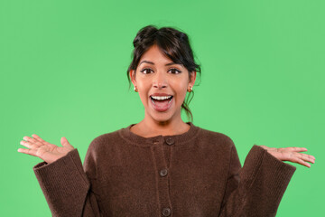 Woman expressing joy and excitement in front of a green background, dressed in a cozy brown...