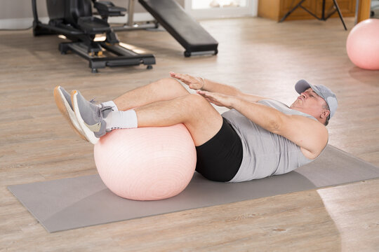 Sit up, fitness and senior man exercising in gym. Mature man doing sit-up cardio workout to reduce belly fat in gym club