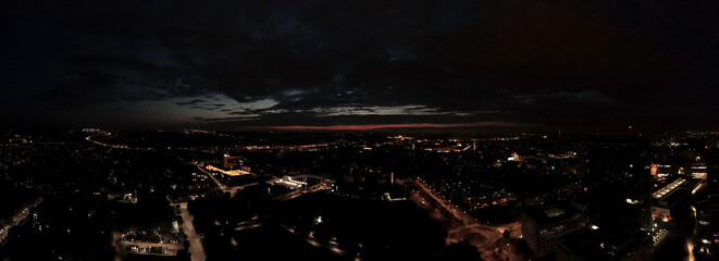 Night aerial panorama of a cityscape with illuminated streets and buildings. The horizon shows a...
