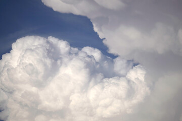 Fluffy white clouds with sunlight highlights against a blue sky, showing detailed textures and...