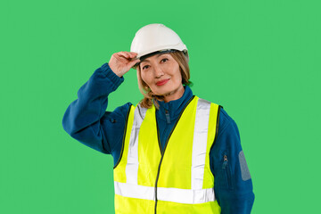 Woman wearing safety gear and helmet smiles confidently while posing against a green background during a construction project