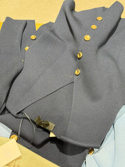 Elegant Black Garment with Gold Buttons . Laid Flat Over Neutral Layers