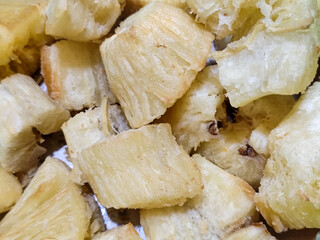 Fried cassava, golden yellow in color and crispy texture can be seen filling the entire frame, showing details of the fibers and soft inside