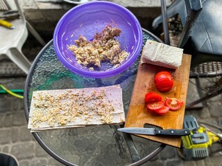 Cook preparing lavash, tomatoes and tuna salad on glass table outdoors