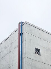 Pipe and vent on concrete factory wall, combining industrial detail with minimal architecture....