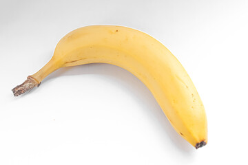 A single ripe yellow banana rests on a plain white background.