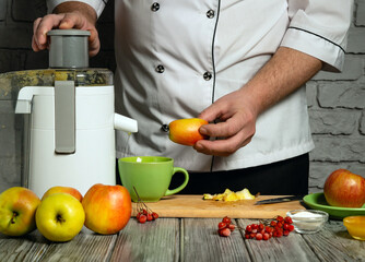 A chef is seen holding an apple while preparing juice using a juicer in a contemporary kitchen....