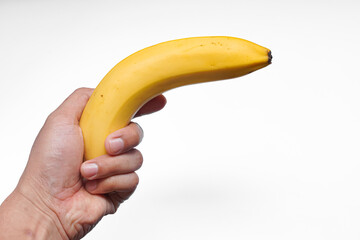 A hand firmly grasps a ripe yellow banana against a clean white background.