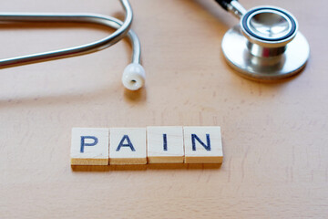 medical concepts. PAIN. word written in wooden letters next to a stethoscope