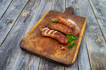 Tasty grilled sausages with herbs on a wooden board