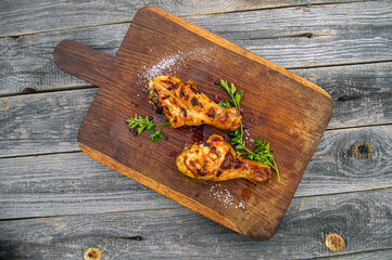 Grilled chicken legs skin-on, bone-in, served on a wooden background