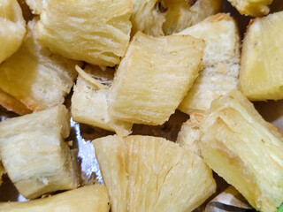 Fried cassava, golden yellow in color and crispy texture can be seen filling the entire frame,...