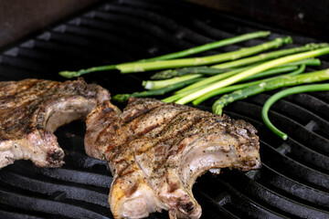 Cooking steak on a gas grill with vegetables.